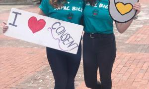 Students with BICE shirts hold I heart consent and SAPAC signs