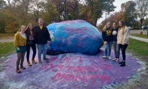 Volunteers stand around Michigan Rock that has been painted for Better Bystander Month