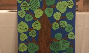 Art piece of tree with leaves that say words of support for survivors 