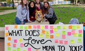 Volunteers posing with corgi and What Does Love Mean to You board